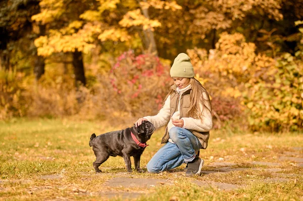 Une fille en vêtements chauds jouant avec un chien dans le parc — Photo