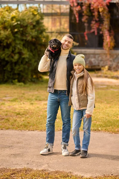 Una familia y su perro de pie en el parque — Foto de Stock