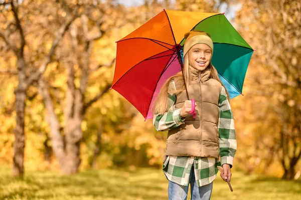 En flicka med ett ljust paraply i en höstpark — Stockfoto