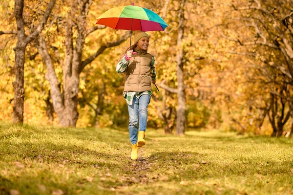 En flicka med ett ljust paraply i en höstpark — Stockfoto
