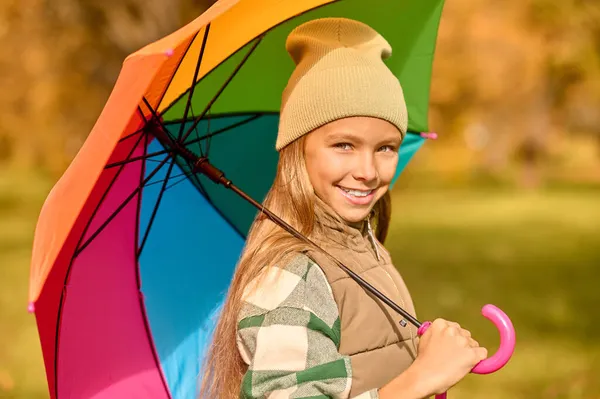 En flicka med ett ljust paraply i en höstpark — Stockfoto