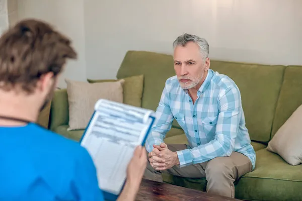 Manlig patient tittar på en läkare med en Urklipp — Stockfoto