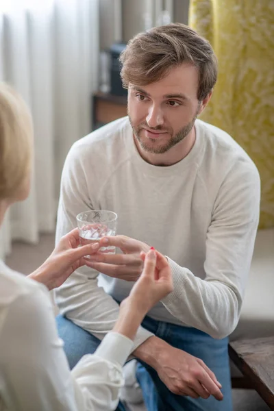 Søn giver sin mor et glas vand, mens hun føler sig utilpas - Stock-foto