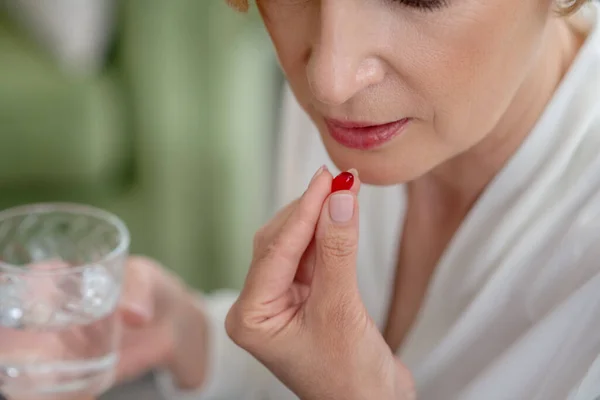Mujer rubia de mediana edad sintiéndose mal y tomando una pastilla — Foto de Stock