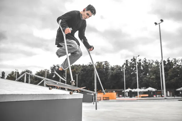 Killen på kryckor hoppar ner från backen på skateboard — Stockfoto