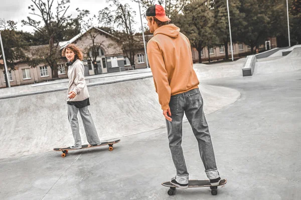 Dziewczyna i facet na deskorolkach ślizgających się w skateparku — Zdjęcie stockowe