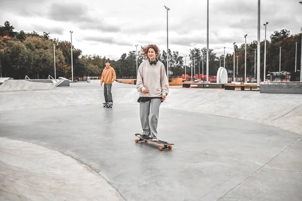 Lächelndes Mädchen fährt Skateboard und Freundin hinterher — Stockfoto