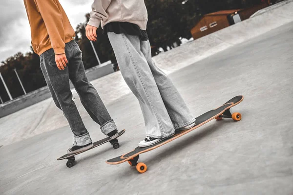 Pernas de dois jovens de pé em skates — Fotografia de Stock