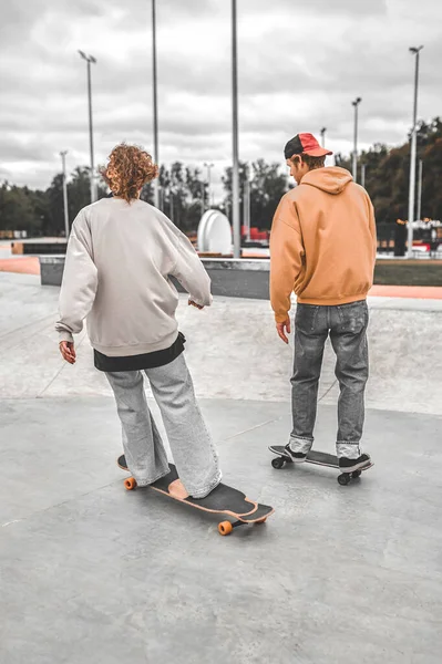 Dos patinadores montando monopatines con la espalda a la cámara — Foto de Stock