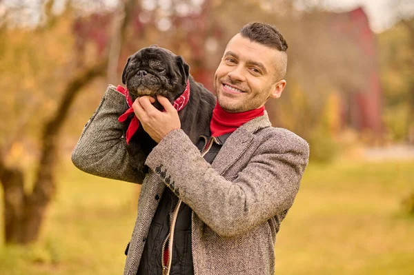 Un uomo felice e sorridente con il suo cane nel parco — Foto Stock