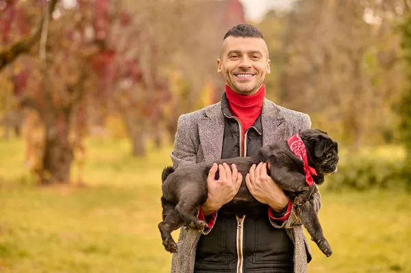 Um homem sorridente feliz com o seu cão no parque — Fotografia de Stock