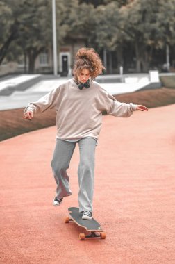 Kaykay süren kız bacağıyla itiyor.