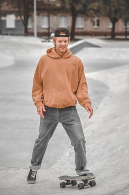 Kaykay parkında gülümseyen adam.