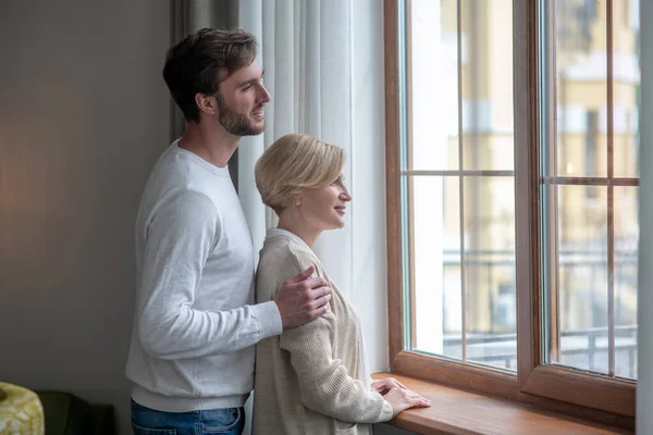 Mother and son standing near the window looking peaceful — Stock Photo, Image