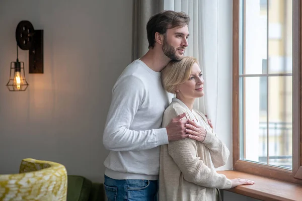 Madre e hijo de pie cerca de la ventana mirando en paz — Foto de Stock