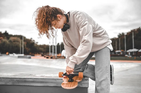 Κορίτσι στέκεται ρύθμιση πάνω από τροχό sketboard — Φωτογραφία Αρχείου