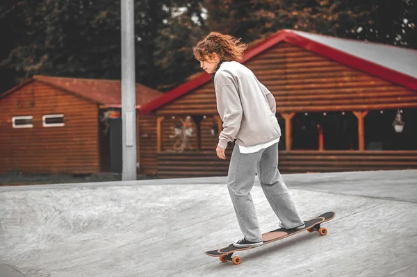 丘から下がるスケートボード上の女の子のプロフィール — ストック写真