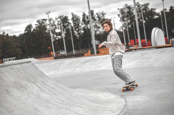 Girl with outstretched hand on skateboard riding in skatepark — ストック写真