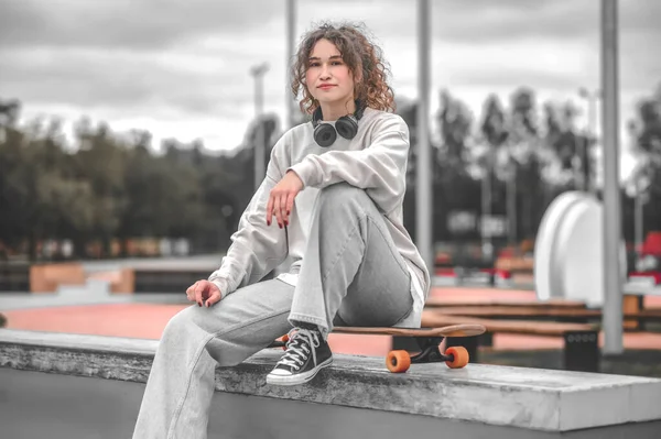 스케이트보드 위에 헤드폰을 앉아 있는 소녀 — 스톡 사진