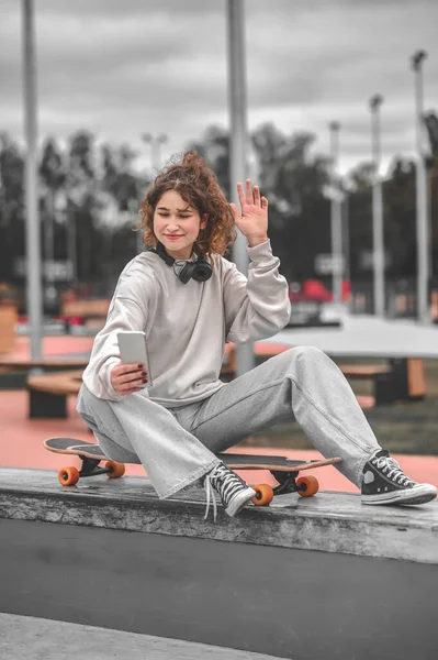 Κορίτσι με σήκωσε το χέρι κάθεται στο skateboard λήψη selfie — Φωτογραφία Αρχείου
