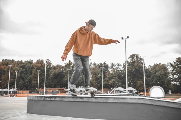 Mann auf Skateboard auf Poller stößt mit Fuß ab — Stockfoto