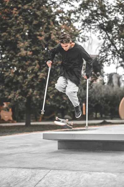 Handikappad kille på kryckor hoppar på skateboard från språngbräda — Stockfoto