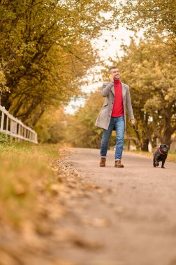 Sabahları köpekle yürüyüşe çıkan ve telefonda konuşan bir adam.