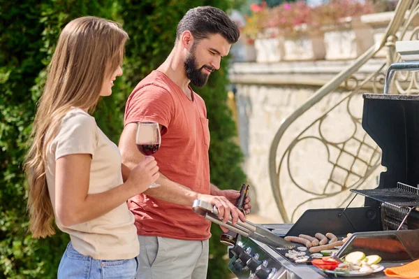 Um jovem couiple cozinhar legumes grelhados juntos e olhando feliz — Fotografia de Stock