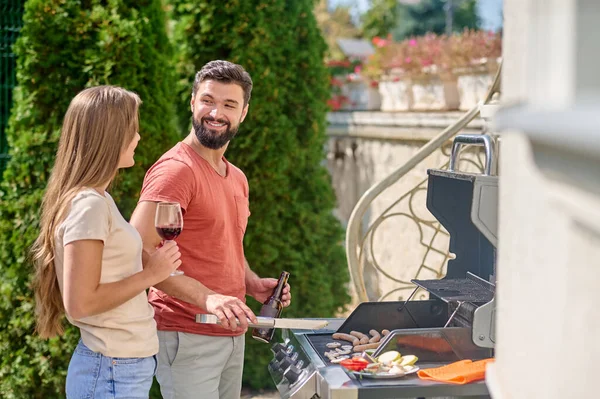 Um jovem couiple cozinhar legumes grelhados juntos e olhando feliz — Fotografia de Stock