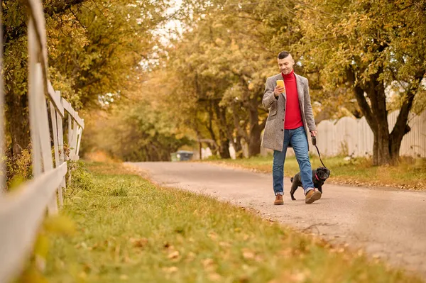Egy férfi kutyát sétáltat a parkban. — Stock Fotó