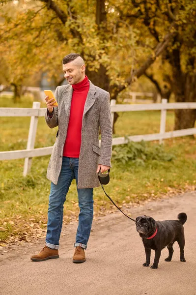 Man having a morning walk with a dog and talking on the phone