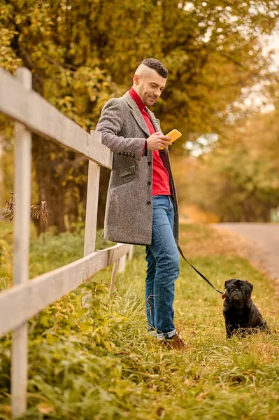 Un uomo con un cane nel parco autunnale — Foto Stock