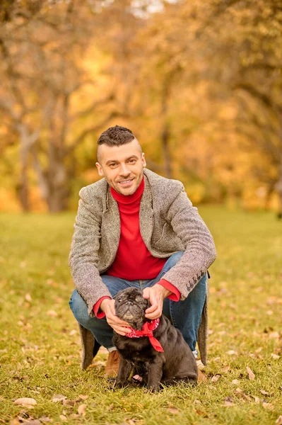 En ung man med sitt husdjur i höstparken — Stockfoto