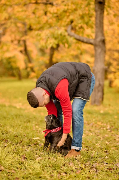 Un hombre de pie en el parque y sosteniendo a su lindo perro — Foto de Stock