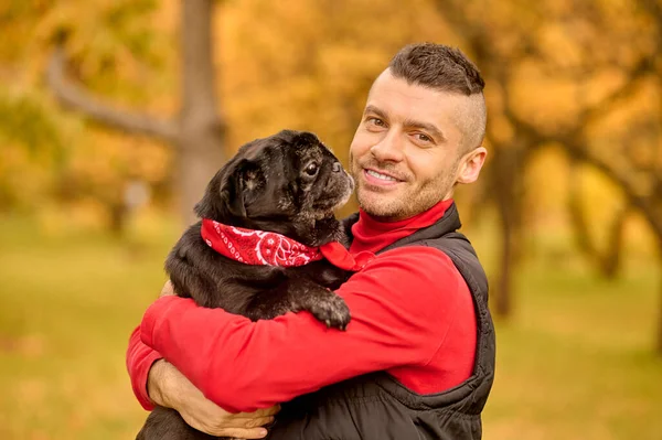 Un uomo in piedi nel parco e abbracciare il suo cane — Foto Stock