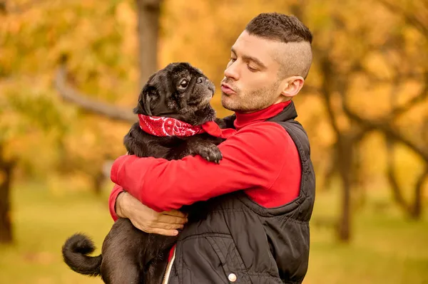 Um homem de pé no parque e abraçando seu cão — Fotografia de Stock