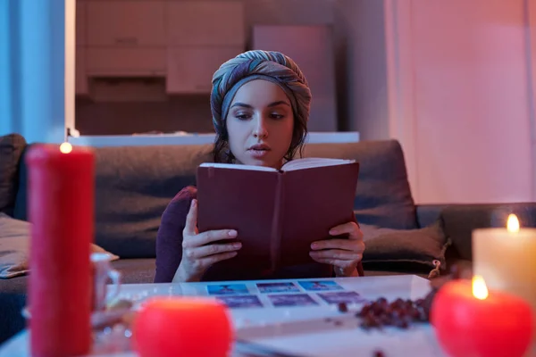 Beginner Tarot card reader in headwear reading a fortune-telling handbook — Stock Photo, Image