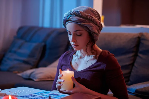 Tranquil soothsayer cleansing her oracle cards with candlelight — Stock Photo, Image