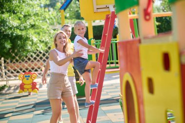 Sevimli bir kız çocuk parkında ailesiyle vakit geçiriyor.