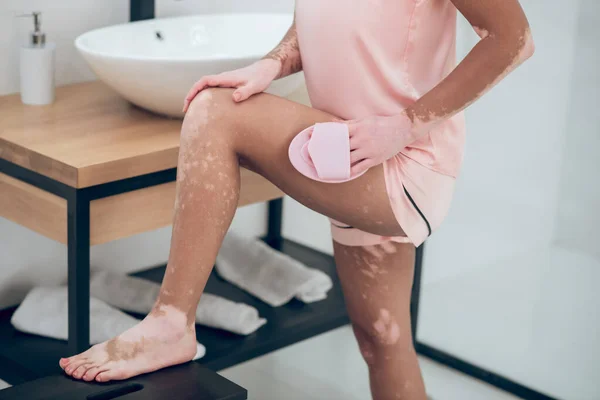 En kvinna i rosa underkläder masserar sina lår — Stockfoto