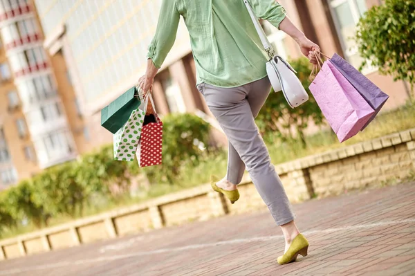 Vista posterior de la mujer caminando felizmente con las compras — Foto de Stock