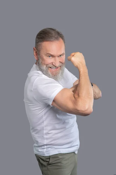 Un hombre maduro con una camiseta blanca mostrando sus músculos — Foto de Stock