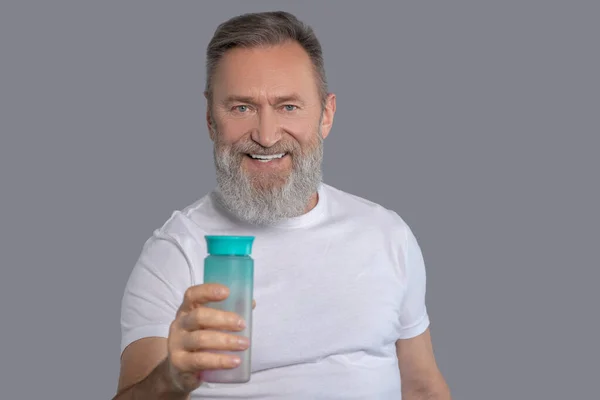 Skäggig man som håller en flaska vatten — Stockfoto