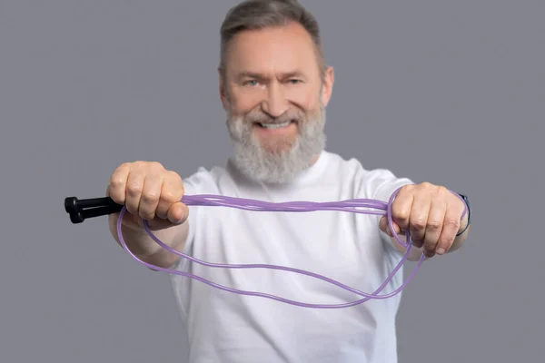 Um homem sorrindo positivo com uma corda de salto nas mãos — Fotografia de Stock