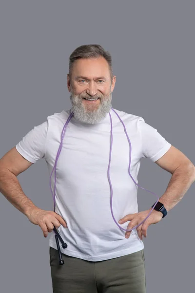 Um homem sorrindo positivo com uma corda de salto nas mãos — Fotografia de Stock