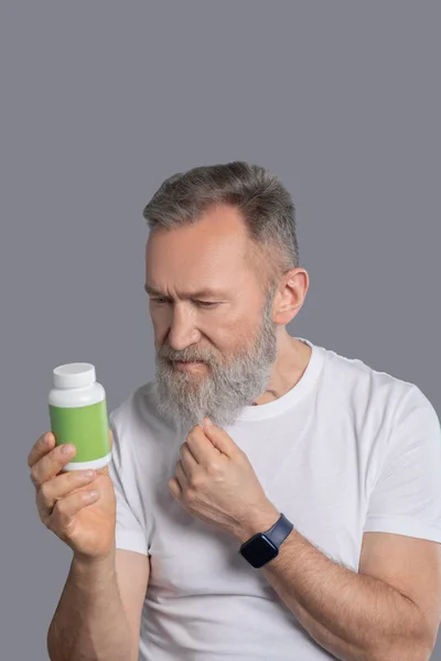 Un hombre barbudo sosteniendo un frasco con vitaminas — Foto de Stock