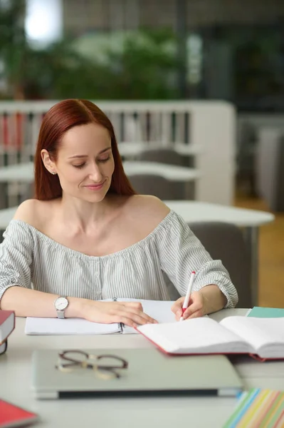 Mulher sentada à mesa escrevendo em caderno — Fotografia de Stock