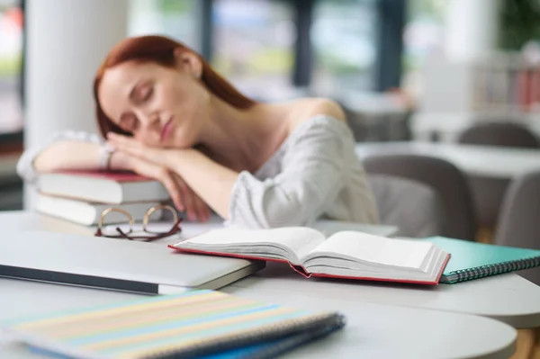 Nő az asztalnál feküdt fej a könyvek alszik — Stock Fotó