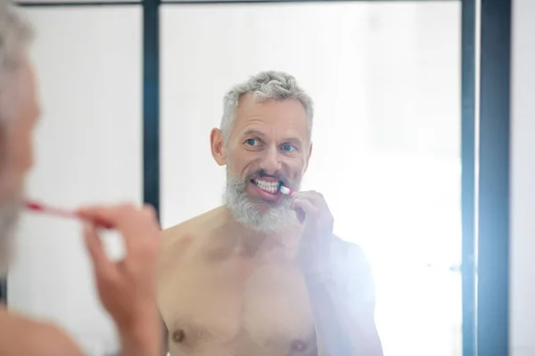 Человек, чистящий зубы перед зеркалом — стоковое фото