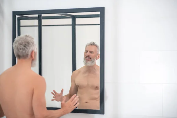 Man topless kijkend naar zijn spiegelbeeld — Stockfoto